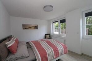 Ein Schlafzimmer mit einem Bett, einem Fenster und einem Bild an der Wand.