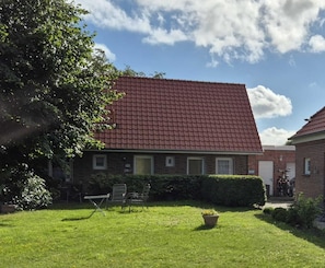 A brick building with a red-tiled roof, a grassy yard, and a bicycle parked outside. - Nice place to stay in an ideal location. (Norden)