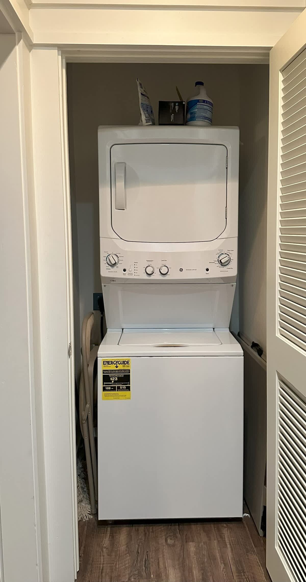A compact washer and dryer unit in a narrow space with a door on one side and a vent on the other.