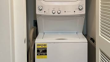 A compact washer and dryer unit in a narrow space with a door on one side and a vent on the other.