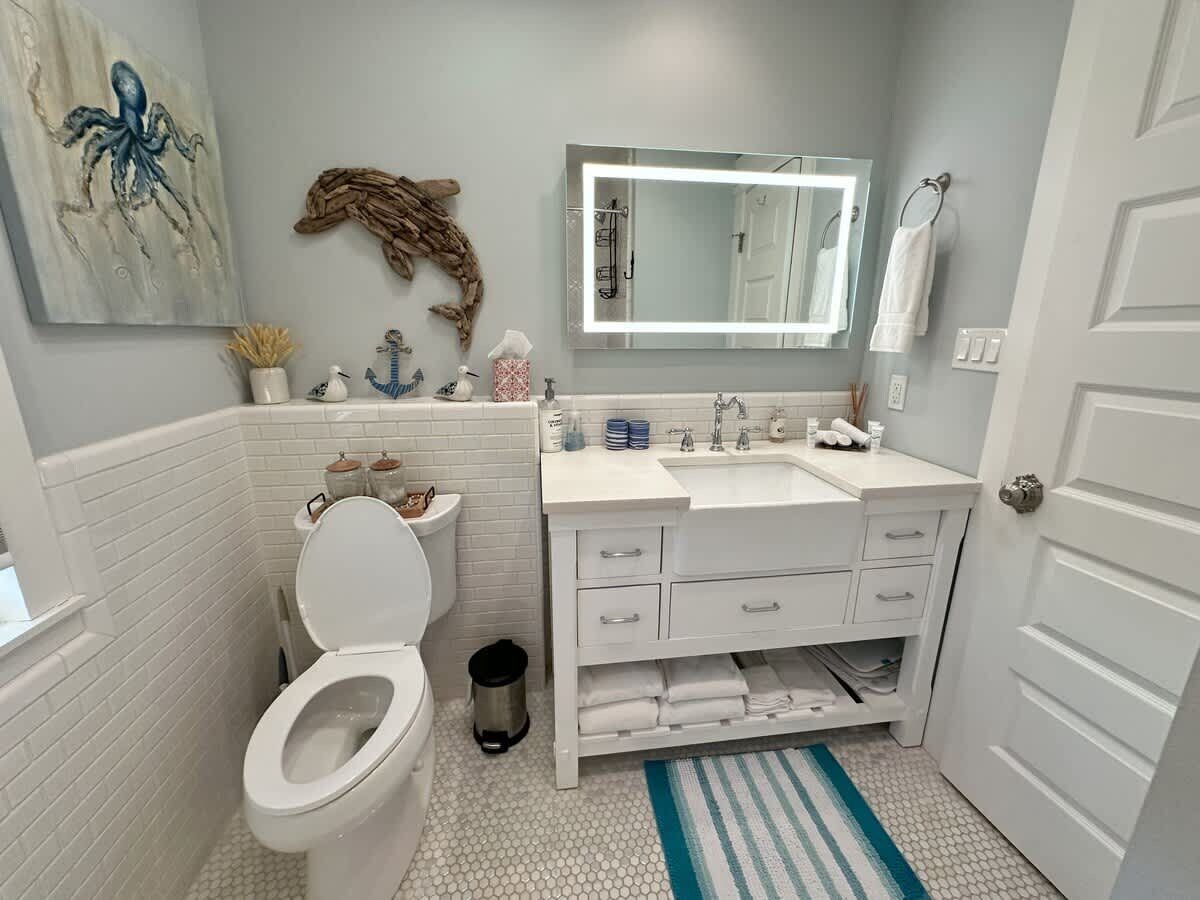 Un baño con inodoro blanco, un lavabo con espejo y un perchero para toallas.