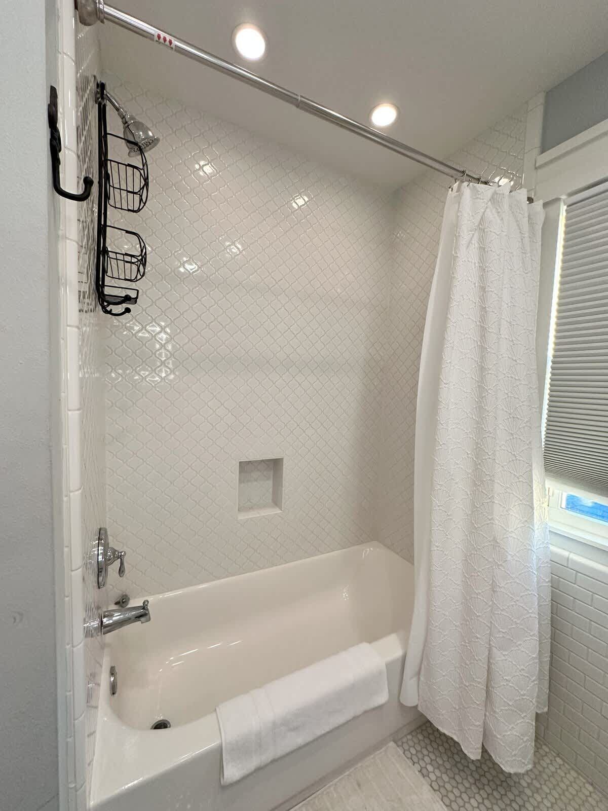 Une salle de bain moderne avec une baignoire sur pieds, un rideau de douche et un porte-serviettes.