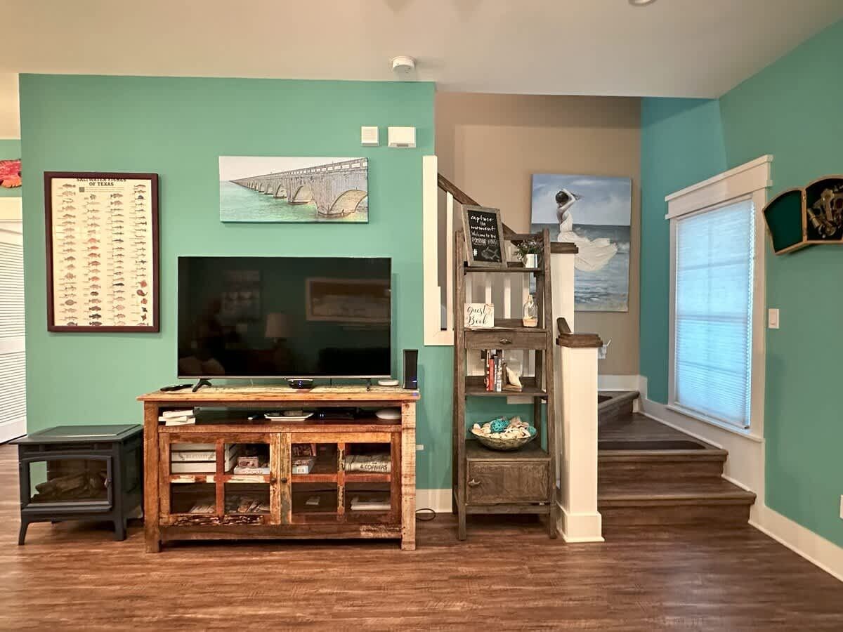 Un salon équipé d’un téléviseur, d’un meuble de rangement en bois et d’un escalier menant à un autre niveau.