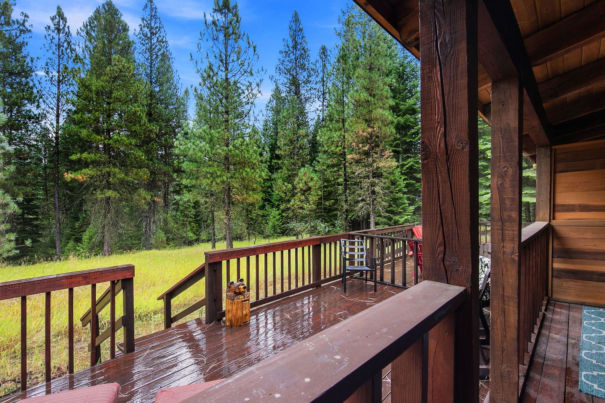 A wooden deck with a railing, overlooking a forested area.
