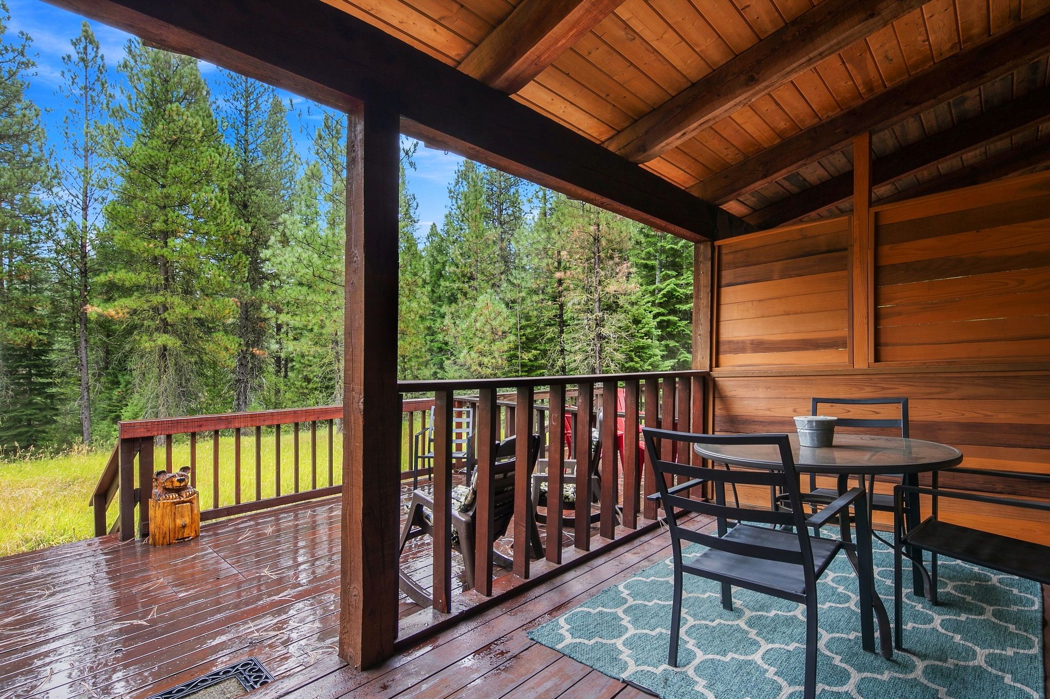 A wooden deck with a table and chairs, overlooking a forest.