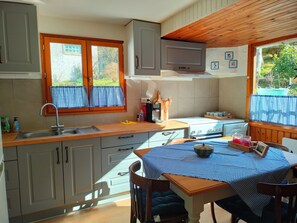 Eine kleine Küche mit Holzarbeitsplatte, Spüle und Fenster mit Karomustertapeten.