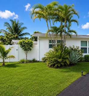 A residential property with a well-maintained lawn, palm trees, and a white fence. - Suite Palma – Private Studio with Pool Access (Deerfield Beach)