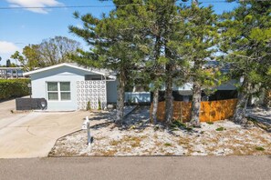 A single-story house with a small attached garage, a fenced yard, and a clear sky. - SonnenHaus - Private Pool - 5 min Walk to Beach (Redington Beach)