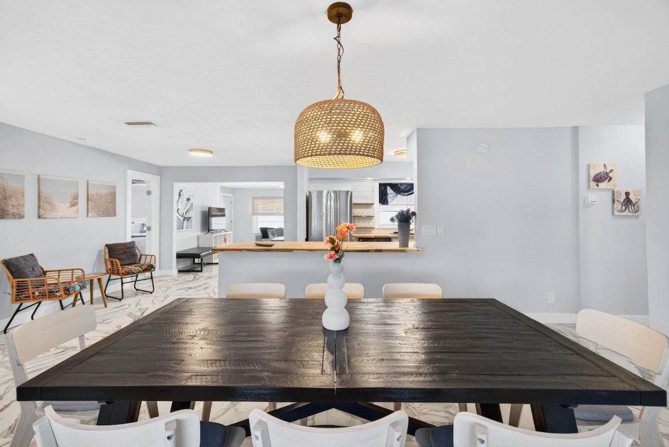 A dining area with a dark wooden table, white chairs, and a hanging light fixture.
