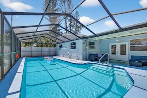 A covered swimming pool with a sunshade, a lounge area with seating, and a view of the surrounding trees. - SonnenHaus - Private Pool - 5 min Walk to Beach (Redington Beach)