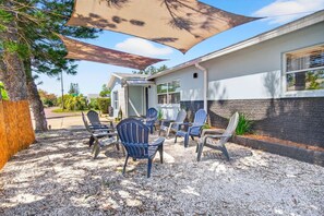 A covered patio area with Adirondack chairs, a small building, and a tree. - SonnenHaus - Private Pool - 5 min Walk to Beach (Redington Beach)