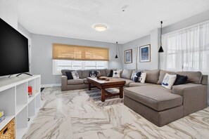 A modern living room with a flat-screen TV, two sofas, a coffee table, and a patterned rug. - SonnenHaus - Private Pool - 5 min Walk to Beach (Redington Beach)