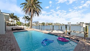 Una piscina con vista despejada del agua, una palmera y un muelle que se adentra en el agua.