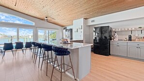 Una cocina moderna con una isla grande, taburetes de bar y vistas al agua.