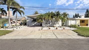 A residential area with a paved driveway leading to a house with a covered patio area.