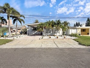 A residential area with a paved driveway leading to a house with a covered patio area. - Coastal Haus|Luxe Waterfront | Dock | Sleeps 10 (Redington Beach)