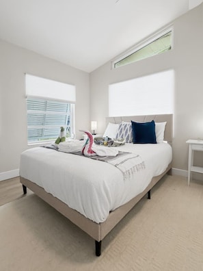 A bedroom with a bed, a bedside table, a lamp, and a window. - Coastal Haus|Luxe Waterfront | Dock | Sleeps 10 (Redington Beach)