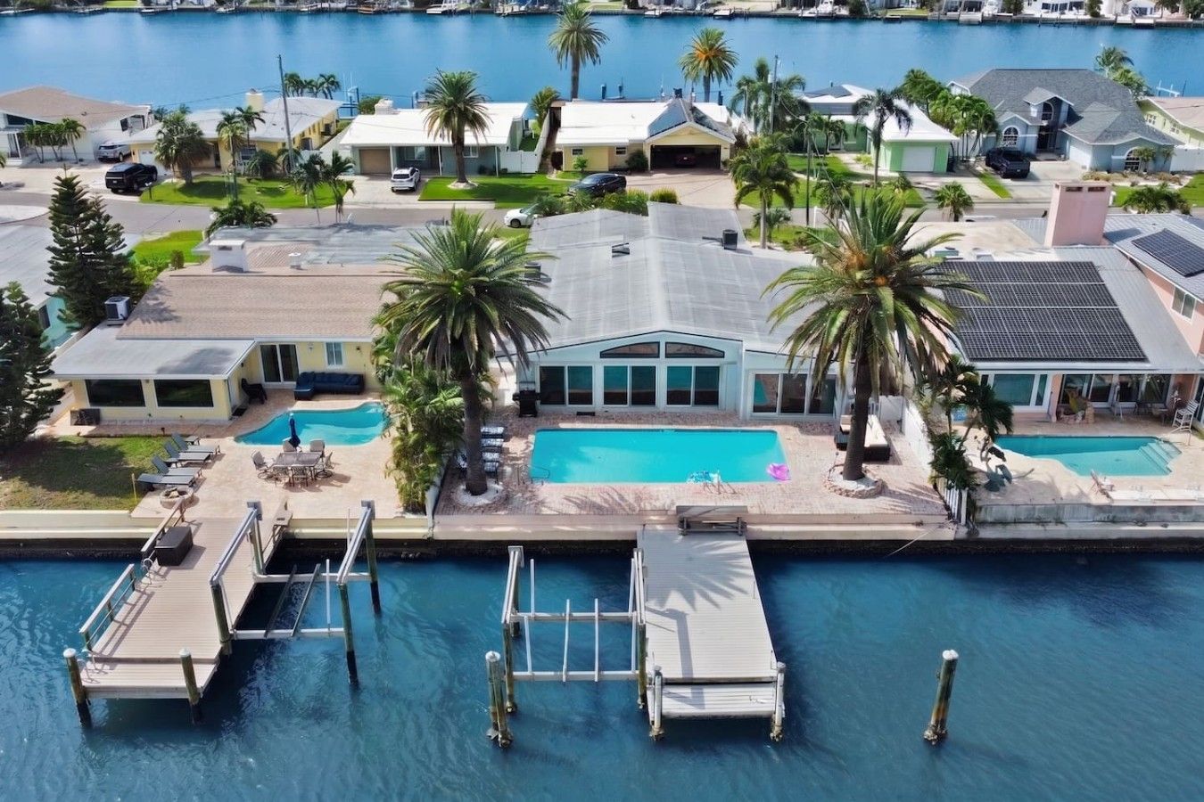 A residential area with a large swimming pool, docked boats, and palm trees.