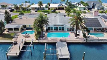 A residential area with a large swimming pool, docked boats, and palm trees.
