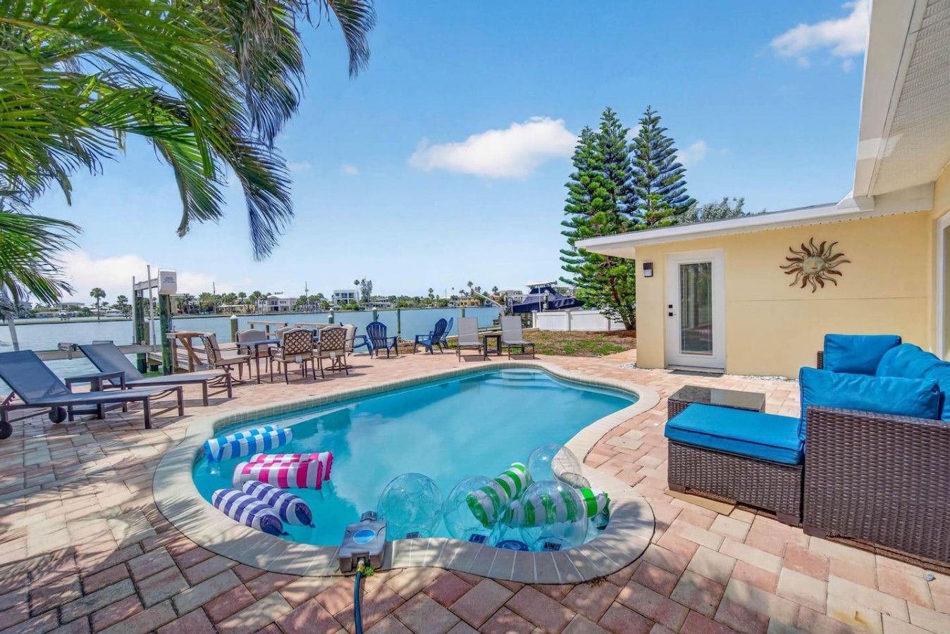 A swimming pool with lounge chairs and inflatable toys, surrounded by a patio area with a view of the water.