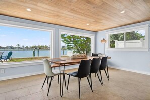 A dining area with a view of a body of water, a wooden ceiling, and a large window. - Sea Haus - Luxury Waterfront Pool Retreat - Beach (Redington Beach)