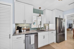 A modern kitchen with white cabinets, stainless steel appliances, and a granite countertop. - Sea Haus - Luxury Waterfront Pool Retreat - Beach (Redington Beach)