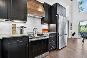 Una cocina moderna con armarios oscuros, una estufa de acero inoxidable y un refrigerador.