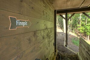 Una cabaña de madera con un letrero que indica 'Firepit' señalando un espacio al aire libre.