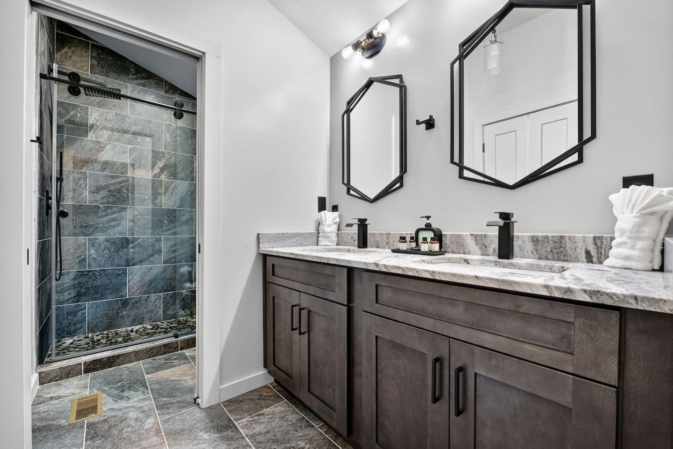 A modern bathroom with a shower, vanity, and two mirrors.