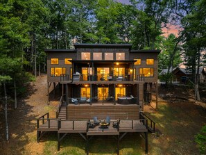 Eine mehrstöckige Holzhütte mit einer Terrasse, umgeben von Bäumen.