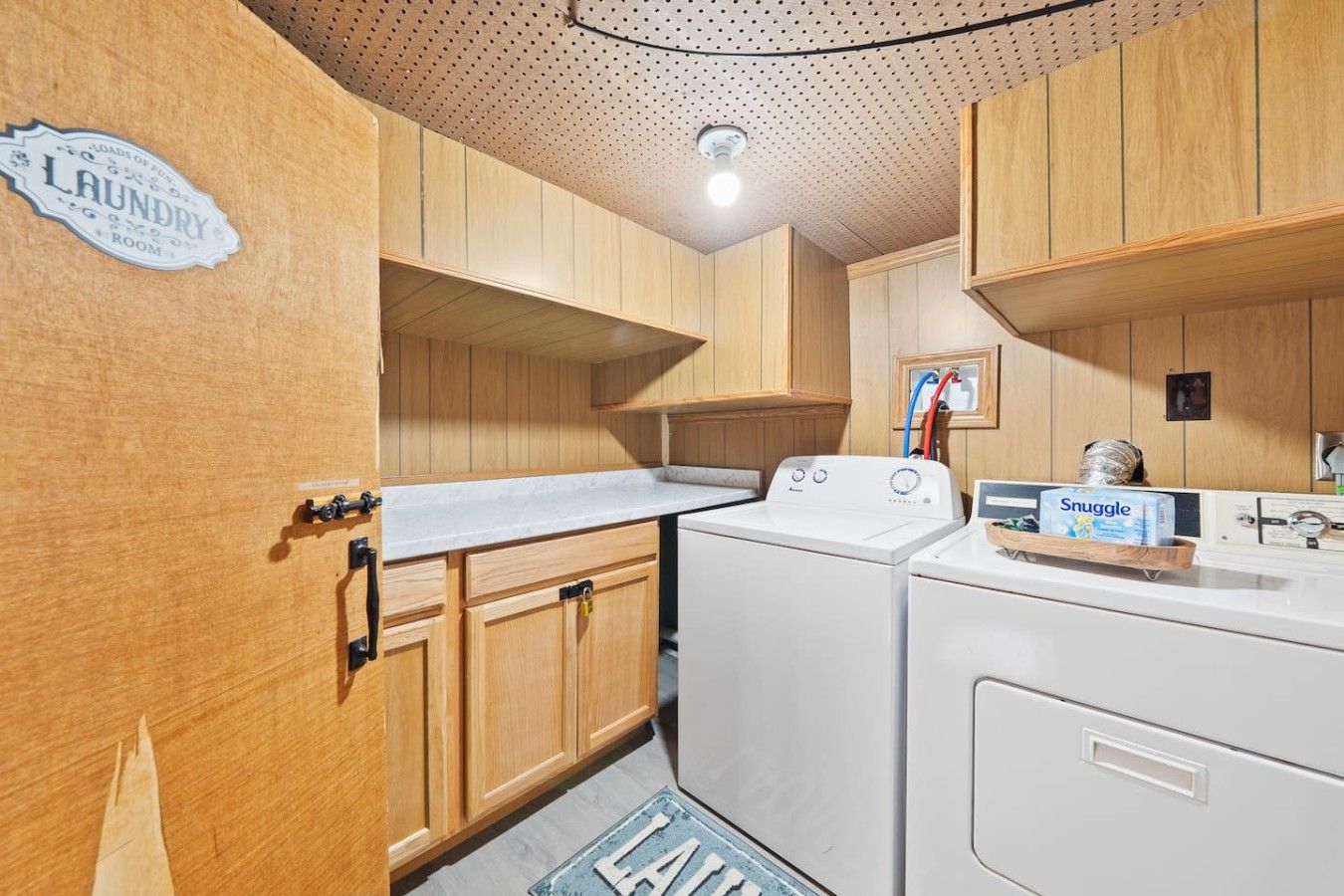 A laundry room with wooden cabinets, a washing machine, and a dryer.