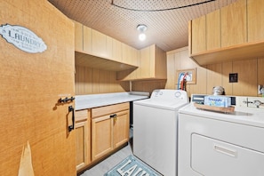 A laundry room with wooden cabinets, a washing machine, and a dryer.