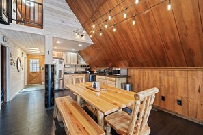 A modern kitchen with wooden cabinets, a dining table, and a bench.