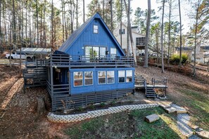 A blue cabin with a balcony, surrounded by trees.