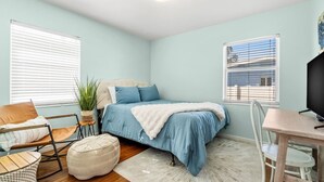 Un dormitorio con cama, una silla, una mesa y un televisor.