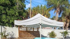 Una terraza cubierta de madera con piscina y una carpa blanca.