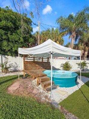 A covered wooden deck with a pool and a white tent.