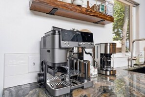A modern kitchen with a built-in espresso machine, a coffee maker, and a marble countertop. - Mountain Haus | 4BR | 3 Decks | Views | Fireplaces (Blue Ridge)