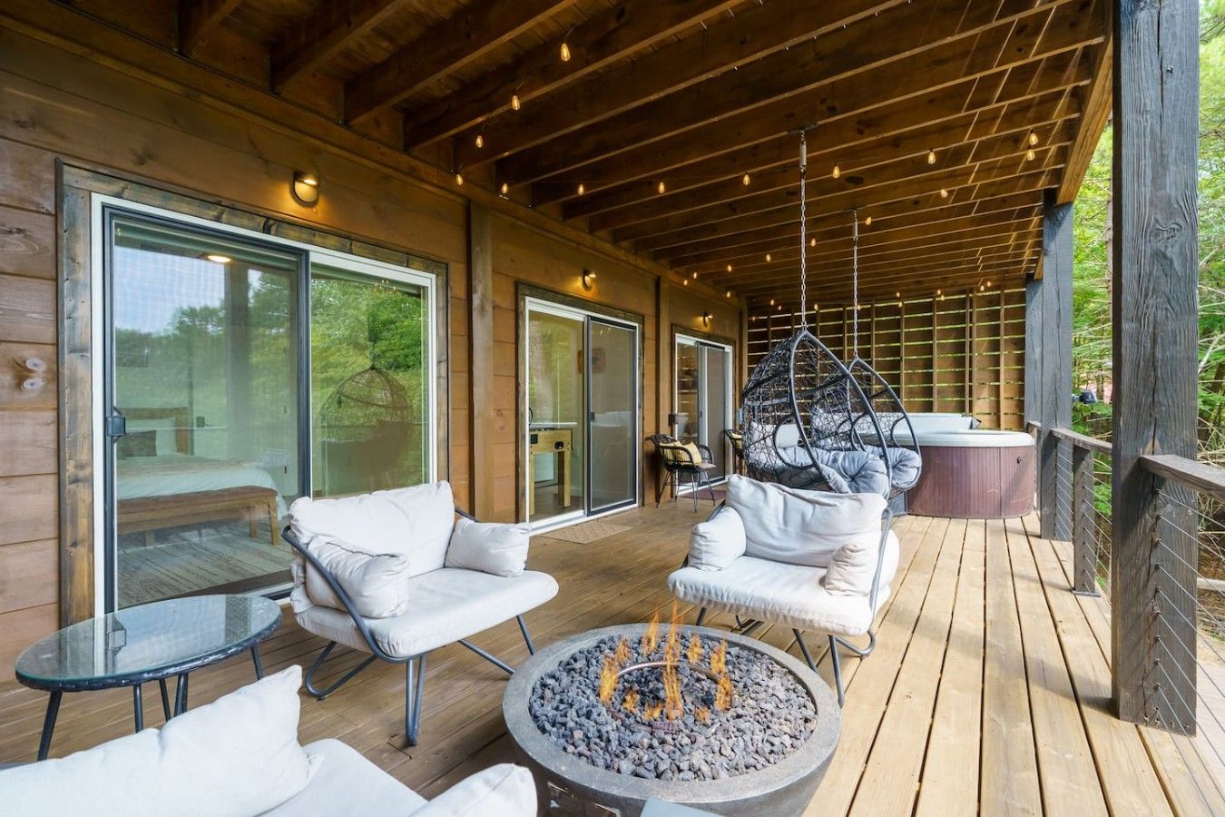 A covered outdoor area with seating, a fire pit, and a hot tub.