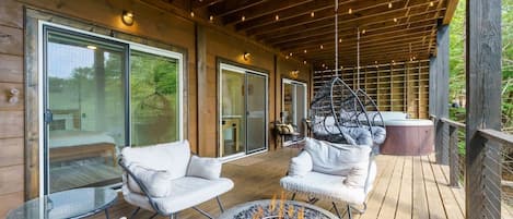 A covered outdoor area with seating, a fire pit, and a hot tub.