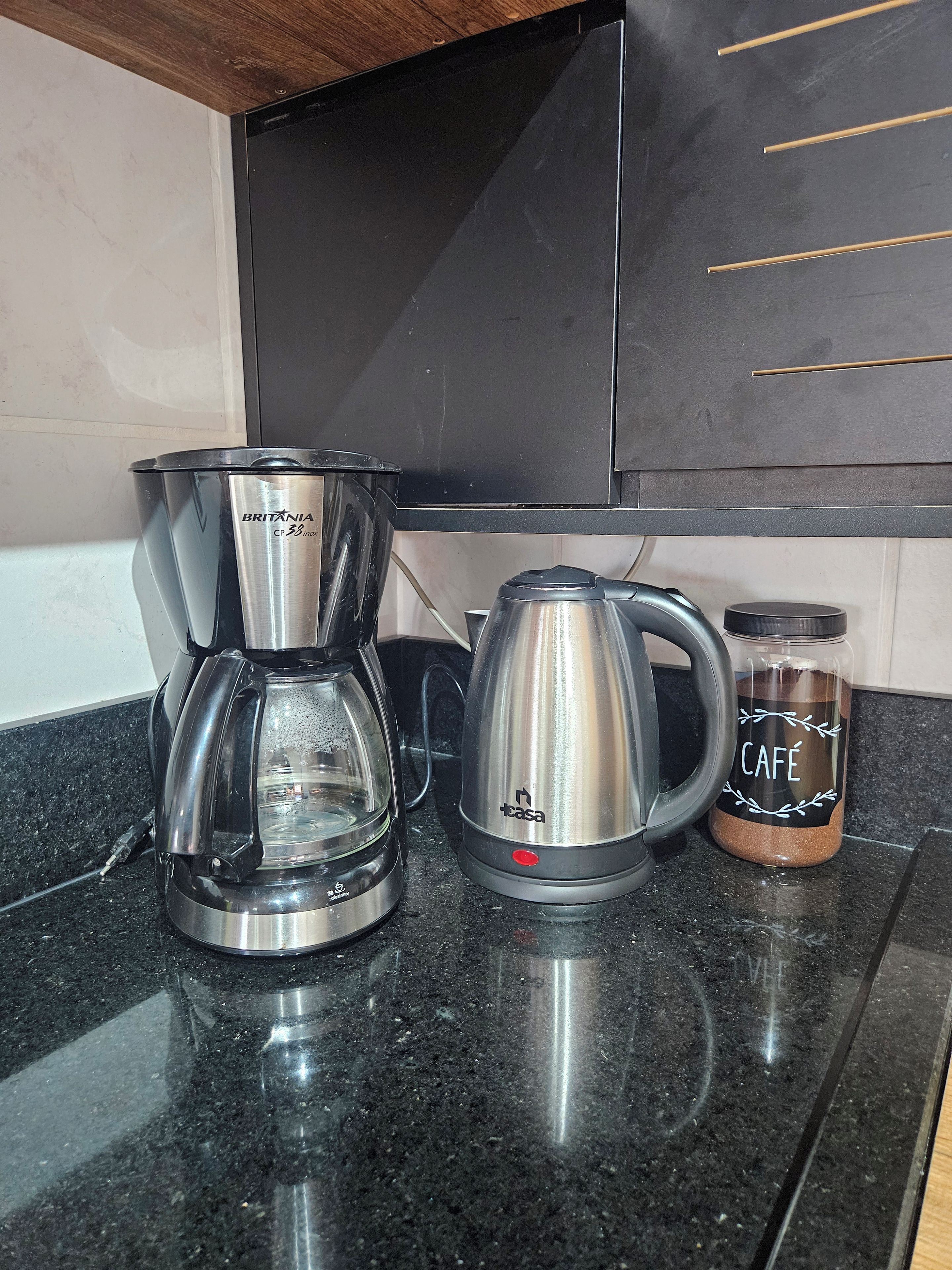Un piano di lavoro in cucina con una macchina del caffè, un bollitore e un barattolo di caffè.