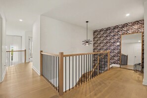 A modern interior with a wooden staircase, a patterned wall, and a hanging light fixture. - Luxe 5-Bed Riverside Getaway PET FRIENDLY, Minutes to Manotick & the Airport (Ottawa)