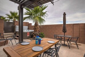 Un patio al aire libre con una mesa de madera, sillas, una parrilla y una palmera.
