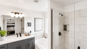 Un bagno moderno con vasca, cabina doccia e mobile lavabo con specchio.
