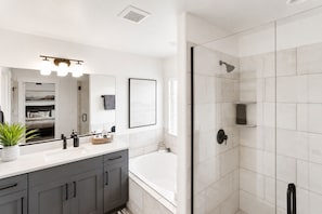 Un baño moderno con bañera, zona de ducha y tocador con espejo.