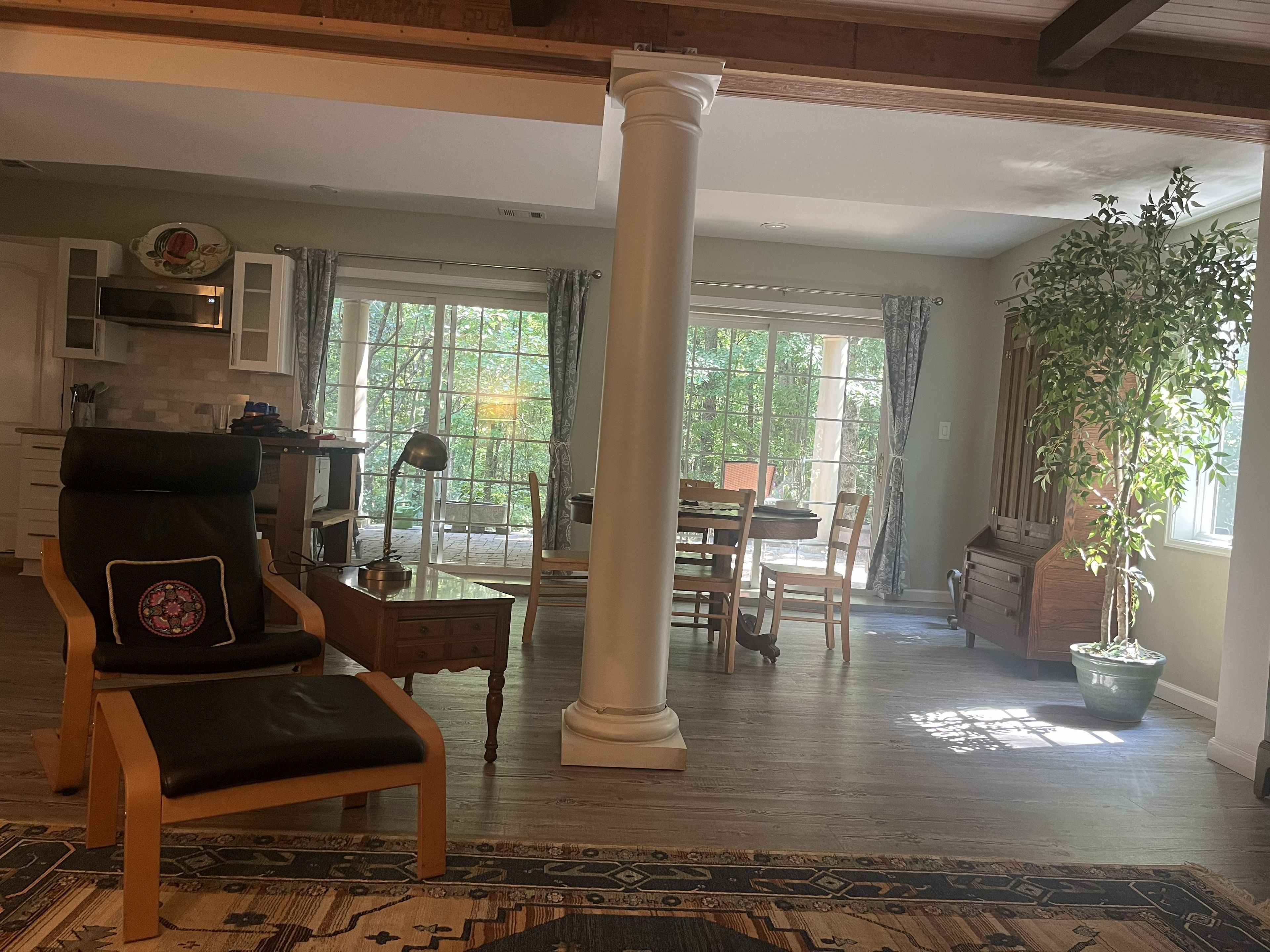 A spacious living area with a large window, a dining table, and a comfortable chair.