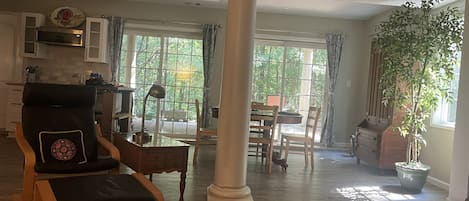 A spacious living area with a large window, a dining table, and a comfortable chair.