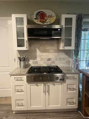 A kitchen with white cabinets, a stainless steel range, and a decorative backsplash. - Beautiful Private Forest Getaway in Peachtree Corners. (Peachtree Corners)