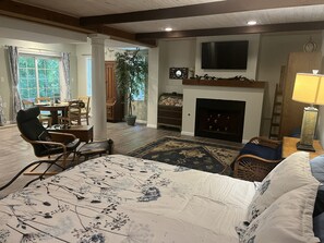 A living room with a fireplace, a television mounted on the wall, and a dining area with a table and chairs. - Beautiful Private Forest Getaway in Peachtree Corners. (Peachtree Corners)
