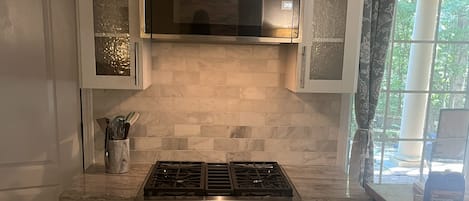 A kitchen with white cabinets, a stainless steel range, and a decorative fruit plate above the microwave.